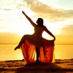 silhueta de mulher ao pôr do sol com vestido fluindo — gestão de energia feminina ciclo hormonal