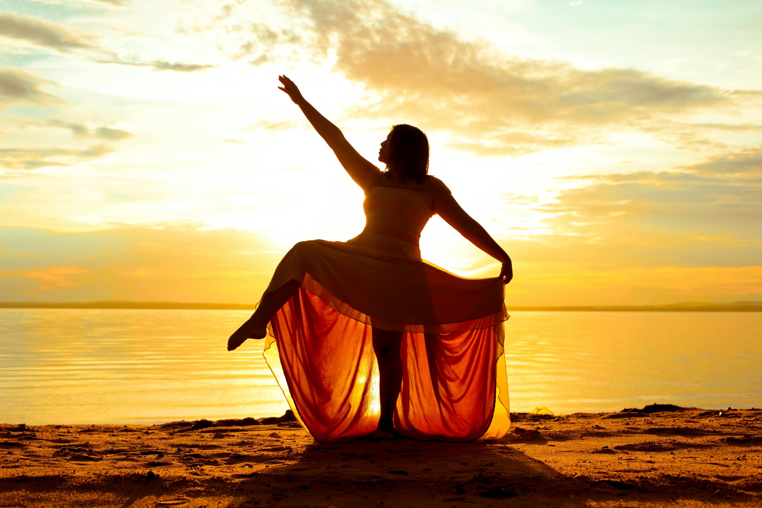 silhueta de mulher ao pôr do sol com vestido fluindo — gestão de energia feminina ciclo hormonal