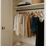 guarda-roupa aberto com poucas peças bem organizadas, cápsula de roupas